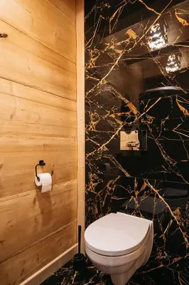 a bathroom with a toilet and a marble wall at NA BALI po góralsku in Poręba Wielka