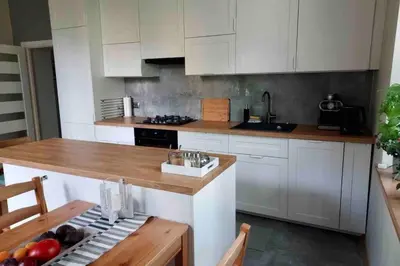 a kitchen with white cabinets and a wooden counter top at Hidden Gem Garden in Kraków
