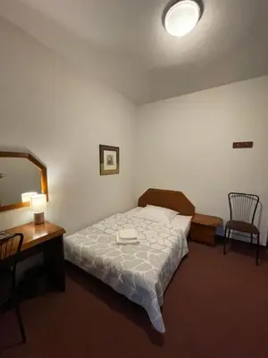 a bedroom with a bed and a desk and a mirror at Pensjonat Południe in Wieliczka
