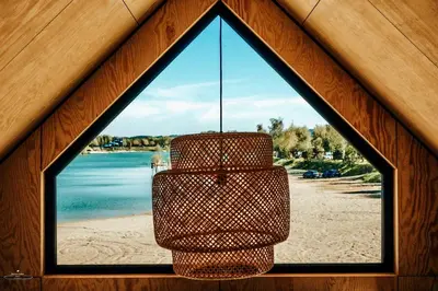 a chandelier hanging from a window with a view of the beach at Wierzbowa przystań in Czchów