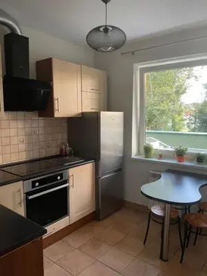 a kitchen with a refrigerator and a table and a window at Apartament Podłęska in Kraków