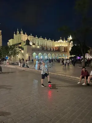 a young boy riding a skateboard in a square at night at Apartament Podłęska in Kraków