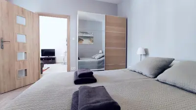 a bedroom with a large white bed with a large mirror at Piłsudskiego 11 by Homeprime in Kraków