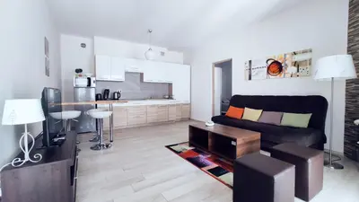 a living room with a black couch and a kitchen at Piłsudskiego 11 by Homeprime in Kraków
