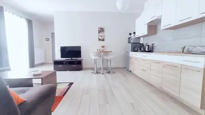 a white kitchen with a couch and a tv in it at Piłsudskiego 11 by Homeprime in Kraków