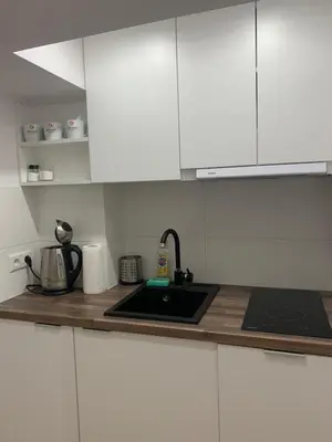 a kitchen counter with a sink and white cabinets at Rzeszowska Apt 01 in Kraków