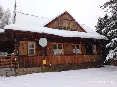a wooden house with snow on the roof at Gospodarstwo Agroturystyczne U Stasików in Spytkowice
