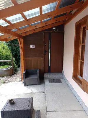 a porch with a wooden pergola with a chair and a door at Gospodarstwo Agroturystyczne U Stasików in Spytkowice