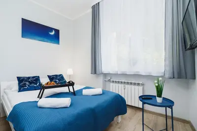 a bedroom with two blue beds and a window at Apartment Smoluchowskiego Cracow by Noclegi Renters in Kraków