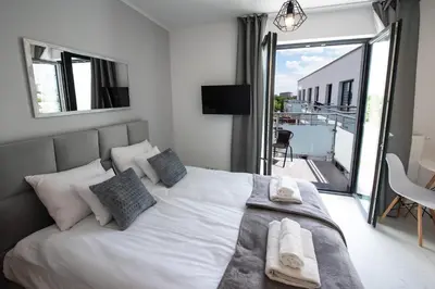 a bedroom with a large white bed with a balcony at Estella Apartment in Kraków