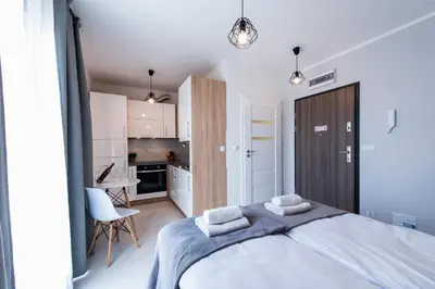 a bedroom with a large bed and a kitchen at Estella Apartment in Kraków