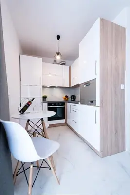 a kitchen with white cabinets and a table and chairs at Estella Apartment in Kraków