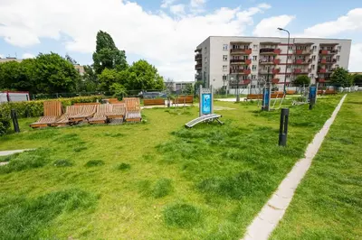 a park with benches in front of a building at Estella Apartment in Kraków