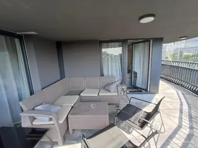 a living room with a couch and chairs on a balcony at APARTAMENTY BARSKA 69 in Kraków