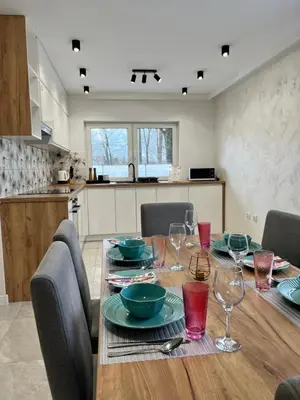 a dining room table with plates and wine glasses at ZATOR Apartamenty Max House, Energylandia in Zator