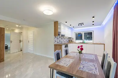 a kitchen and dining room with a wooden table and chairs at ZATOR Apartamenty Max House, Energylandia in Zator