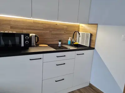 a kitchen with white cabinets and a microwave at Apartament Łąki18 in Wadowice