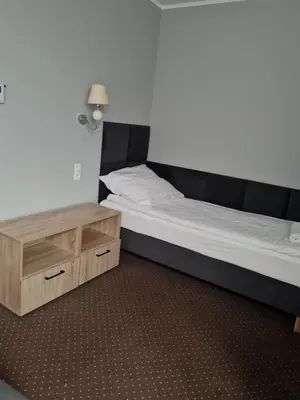 a bedroom with a bed and a night stand at Hotel Savana in Kłaj