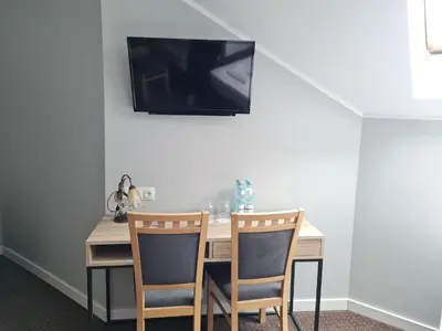 a dining room table with two chairs and a television on the wall at Hotel Savana in Kłaj
