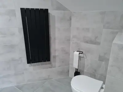 a bathroom with a white toilet and a black window at Hotel Savana in Kłaj