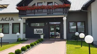 a building with a balcony with red flowers on it at Hotel Savana in Kłaj