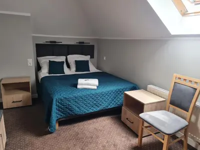 a bedroom with a bed with a blue blanket and a chair at Hotel Savana in Kłaj