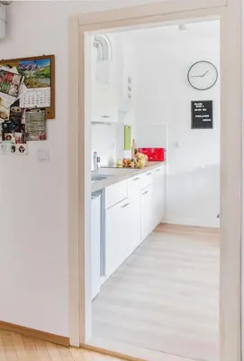 a kitchen with white cabinets and a white floor at Cosy Apartment 2 in Kraków