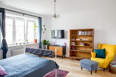 a bedroom with a bed and a yellow chair at Cosy Apartment 2 in Kraków