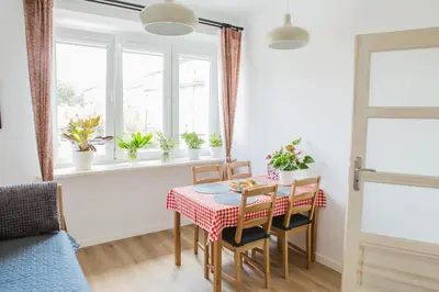 a dining room with a table and chairs and windows at Cosy Apartment 2 in Kraków