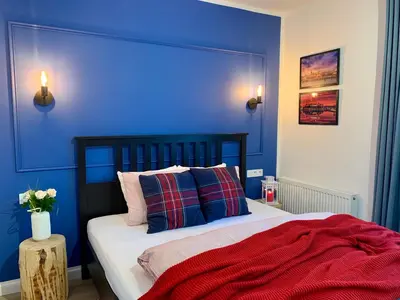 a blue bedroom with a bed with a red blanket at RiversideSuite. Krakow in Kraków