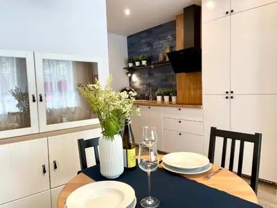 a kitchen with a table with plates and a vase with flowers at RiversideSuite. Krakow in Kraków