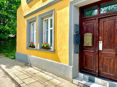 a house with a wooden door and two windows with flowers at RiversideSuite. Krakow in Kraków