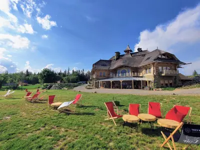 a group of chairs and tables in front of a large house at Wrzosowy Dwór - SPA in Skomielna Czarna