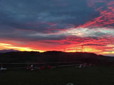 a sunset with chairs in a field with the sky at Wrzosowy Dwór - SPA in Skomielna Czarna