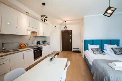 two beds in a small room with a kitchen at Drwinka Park Apartment in Kraków