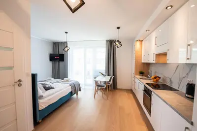a bedroom with a bed and a kitchen with a table at Drwinka Park Apartment in Kraków