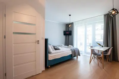 a bedroom with a bed and a desk and a table at Drwinka Park Apartment in Kraków