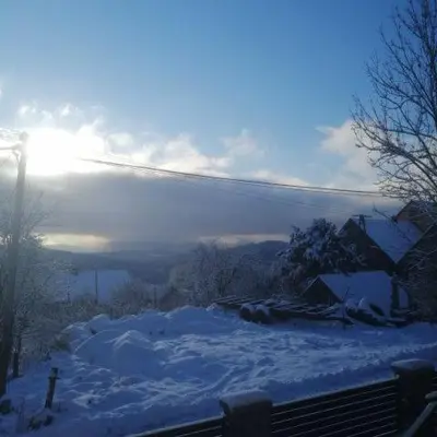 a snow covered hill with the sun in the background at Michalka 1 - Domki pod Leskowcem in Targoszów