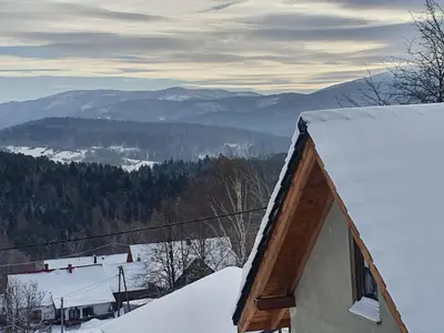 a snow covered house with a view of a mountain at Michalka 1 - Domki pod Leskowcem in Targoszów