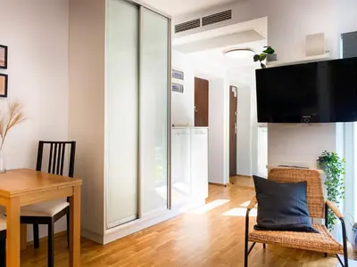 a living room with a dining table and a tv at Charming Studio for couples in the heart of Cracow in Kraków
