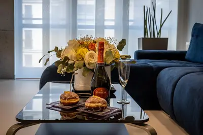 a glass table with a bottle of wine and two pastries at Ekskluzywny Apartament Garden Residence *Basen/Siłownia* in Kraków