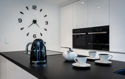 a clock on a wall above a kitchen counter with cups at Ekskluzywny Apartament Garden Residence *Basen/Siłownia* in Kraków