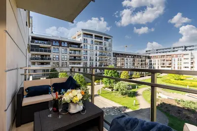 a balcony with a couch and a table with flowers at Ekskluzywny Apartament Garden Residence *Basen/Siłownia* in Kraków