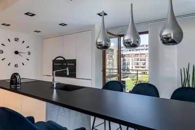 a kitchen with a black counter and a clock on the wall at Ekskluzywny Apartament Garden Residence *Basen/Siłownia* in Kraków