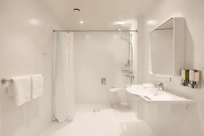 a white bathroom with a shower and a sink at Hampton by Hilton Krakow Airport in Balice