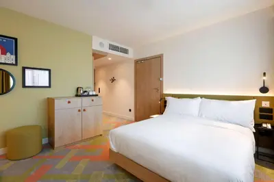 a bedroom with a large white bed and a cabinet at Hampton by Hilton Krakow Airport in Balice