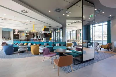 a lobby with a blue couch and tables and chairs at Hampton by Hilton Krakow Airport in Balice