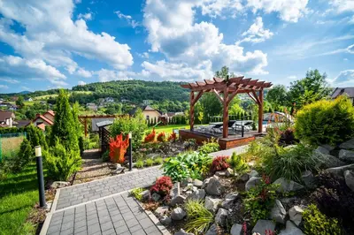 a garden with a wooden gazebo and a landscaping at Apartamenty Black Lion in Pcim