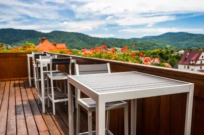 a row of tables and chairs on a deck with flowers at Apartamenty Black Lion in Pcim