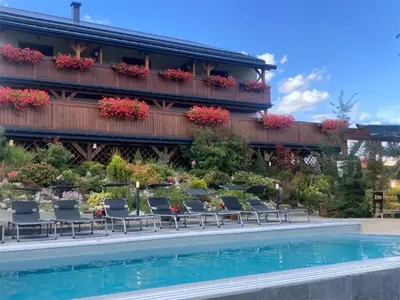 a swimming pool with chairs and a building at Apartamenty Black Lion in Pcim